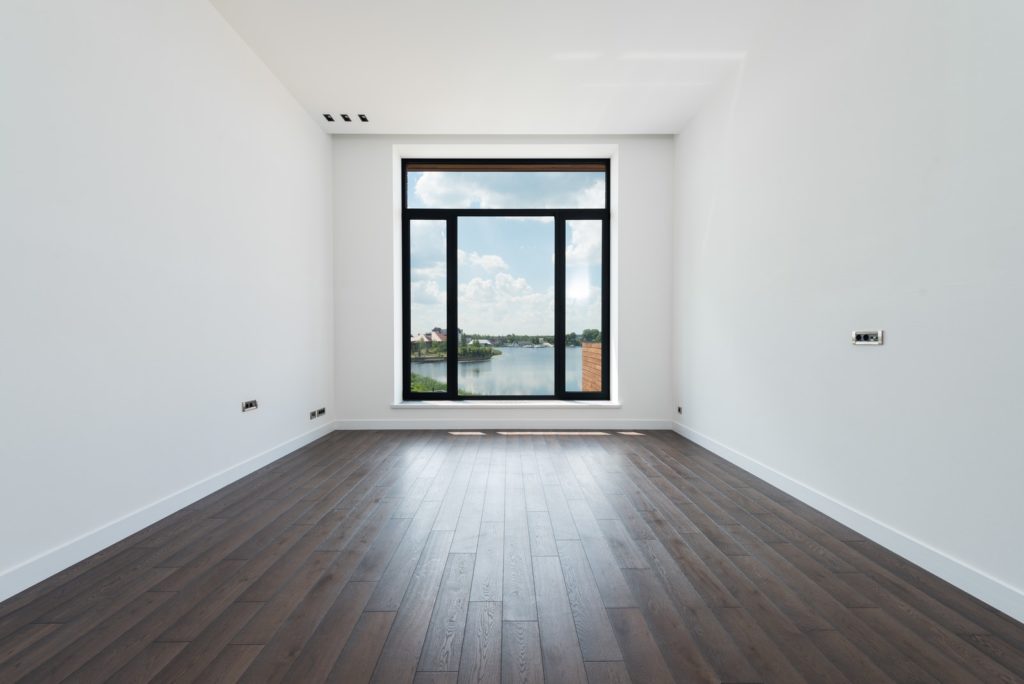 Interior of modern spacious light room with wooden laminate floor white walls and panoramic windows drywall